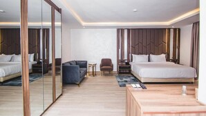 A modern hotel room with a large bed, a sofa, a small table, and a mirror.