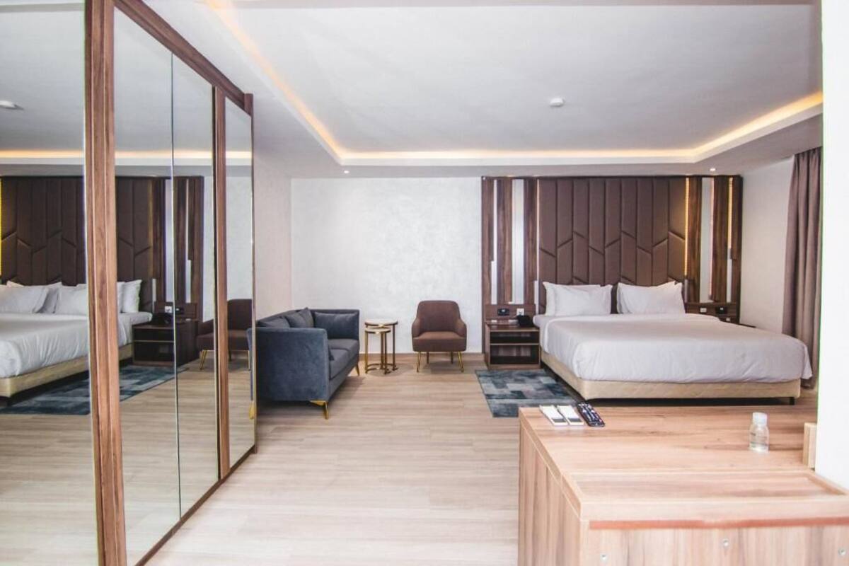 Une chambre d’hôtel moderne avec un grand lit, un canapé, une petite table et un miroir.