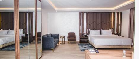 Una habitación de hotel moderna con una cama grande, un sofá, una mesita y un espejo.