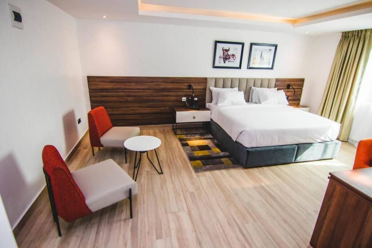 Une chambre d’hôtel moderne avec un grand lit, une petite table, deux chaises et une table de chevet.