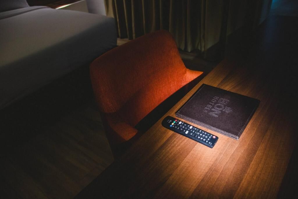 Une télécommande et un livre sur une table en bois, dans une pièce faiblement éclairée.