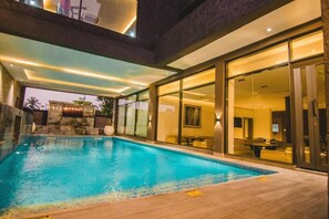 A modern indoor swimming pool with glass walls and a stone facade. - The Safron Hotel Ikeja (Lagos)