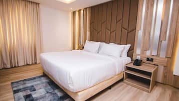 Quarto de hotel moderno com cama grande, cabeceira de madeira e mesa de cabeceira com telefone.