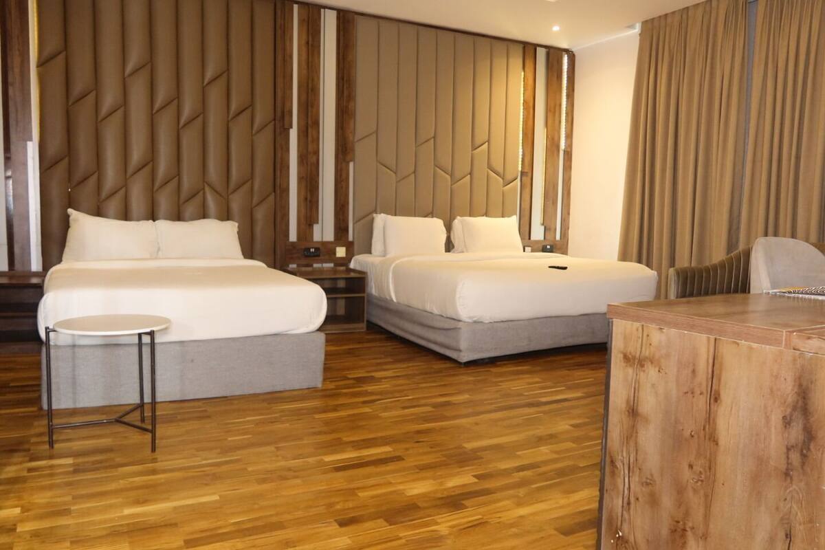 Une chambre d’hôtel avec deux lits, une petite table ronde et une table d’appoint en bois.