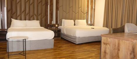 A hotel room with two beds, a small round table, and a wooden side table.