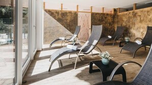 Un espacio al aire libre iluminado por el sol con sillones modernos y una mesita con un florero.