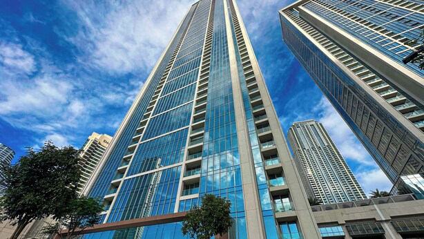 A high-rise building with a modern glass facade and a clear blue sky in the background. - WelHome - Exclusive 2BR Apartment in Downtown Forte (Dubai)
