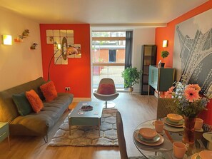 Relax in this stylish living space with a sofa, coffee table, and dining area, offering a view of the outside and a touch of greenery.
