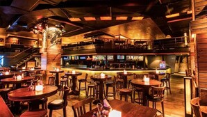 A restaurant with multiple dining tables and chairs, a bar area, and a staircase leading to an upper level. - Tranquil 2bhk Oasis in the Heart of Gurugram (Gurugram)