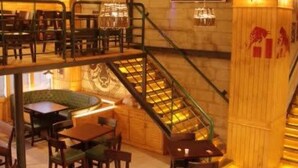 A restaurant with a wooden interior, a staircase, and tables and chairs arranged for dining. - Tranquil 2bhk Oasis in the Heart of Gurugram (Gurugram)