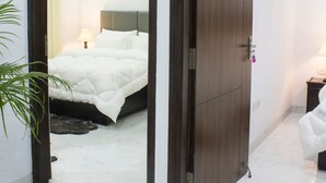 A bedroom with a bed, bedside table, lamp, and an air conditioning unit. - Tranquil 2bhk Oasis in the Heart of Gurugram (Gurugram)