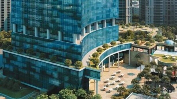 A modern high-rise building with a glass facade, surrounded by other buildings and a landscaped area with trees and a small pavilion. - Tranquil 2bhk Oasis in the Heart of Gurugram (Gurugram)