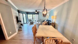 A dining area with a long table, wicker chairs, a ceiling fan, and a view to a balcony. - Tropical getaway awaits!!! (Saint Augustine)