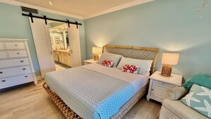A bedroom with a bed, nightstands, a dresser, and a door leading to a bathroom. - Tropical getaway awaits!!! (Saint Augustine)
