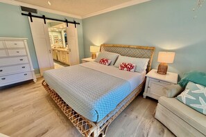 A bedroom with a bed, nightstands, a dresser, and a door leading to a bathroom. - Tropical getaway awaits!!! (Saint Augustine)