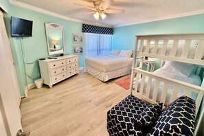 A bedroom with a crib, a bed, a dresser, a television, and a window with blinds. - Tropical getaway awaits!!! (Saint Augustine)