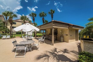 A pool area with lounge chairs and umbrellas, a stone wall, and a sign indicating pool rules.