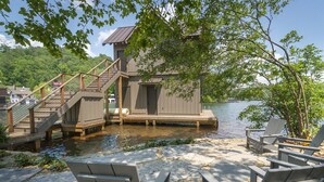 A dock with chairs, a wooden staircase, and a building by the water.