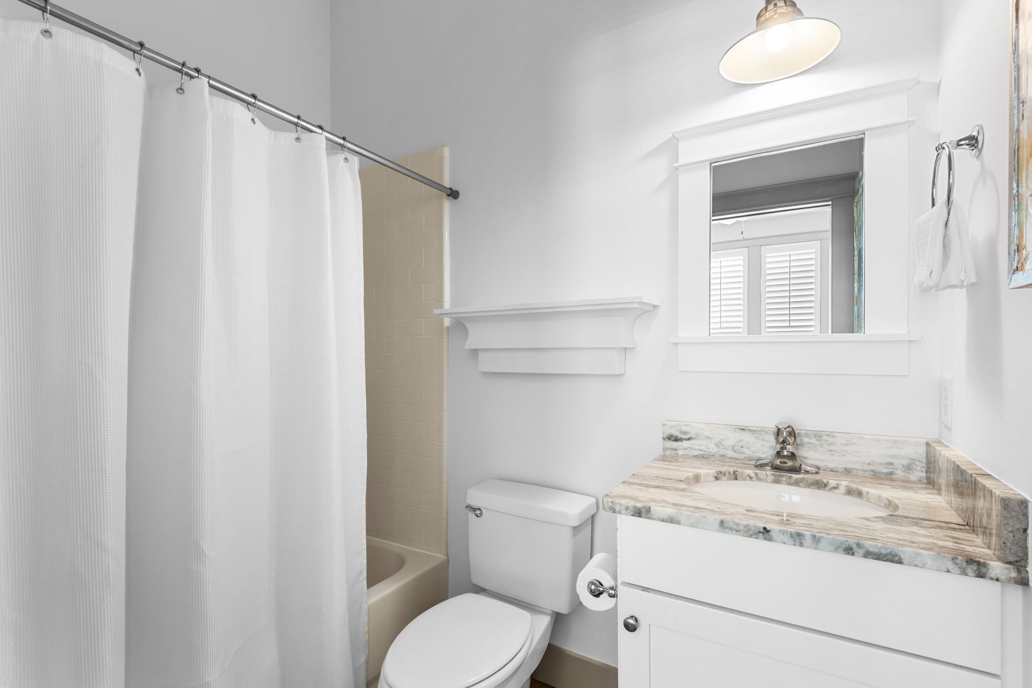 A bathroom with a toilet, sink, mirror, and shower curtain.