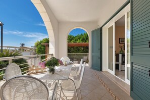A balcony with a table and chairs, a potted plant, and a view of greenery. - 3945 Villa Ko by Barbarhouse (Otranto)