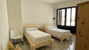 A bedroom with two wooden beds, a white chair, a wooden wardrobe, and a large window. - RESIDENCE ORIZZONTE BLU (Morciano di Leuca)