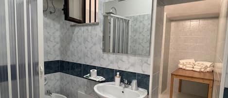 A bathroom with a toilet, bidet, sink, and a shower area.