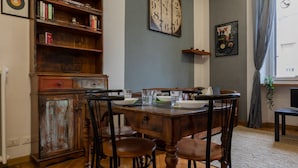 Un comedor con una mesa de madera, sillas, una estantería y un reloj de pared.