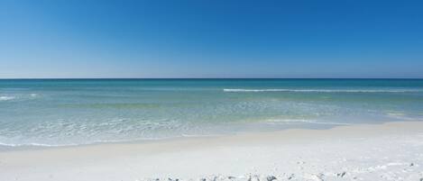 Une plage de sable blanc bordée d’une eau d’un bleu cristallin.