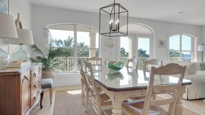 A spacious dining area with a glass table, white chairs, and a view of the outdoors through large windows. - 5 Minutes to Beach - Large Complex Pool (Santa Rosa Beach)