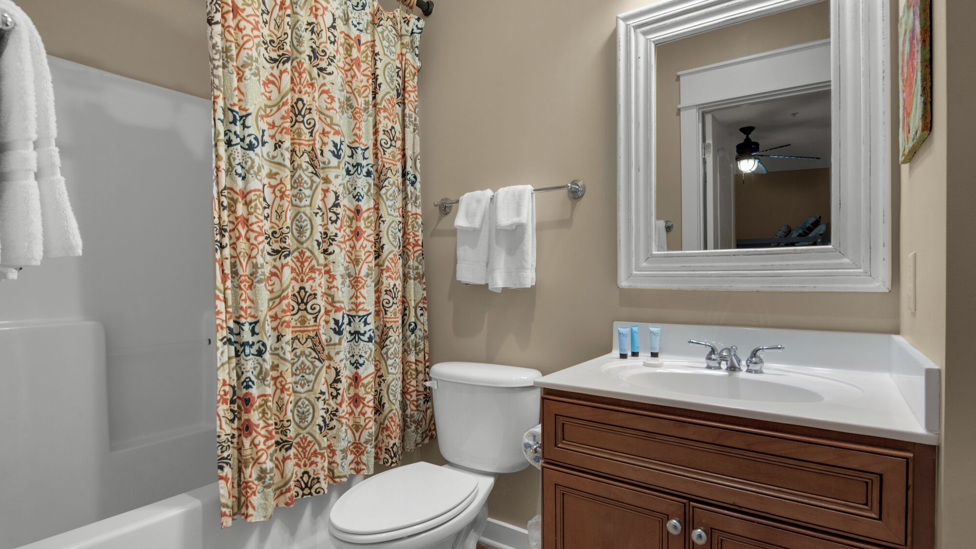 A bathroom with a toilet, sink, vanity, and a shower curtain.