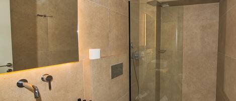 A modern bathroom with a large sink, mirror, and glass-enclosed shower.