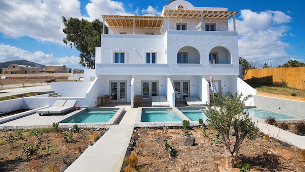 A modern white villa with a pool, outdoor seating, and a view of the surrounding landscape. - Moonlight Hotel (Santorini)