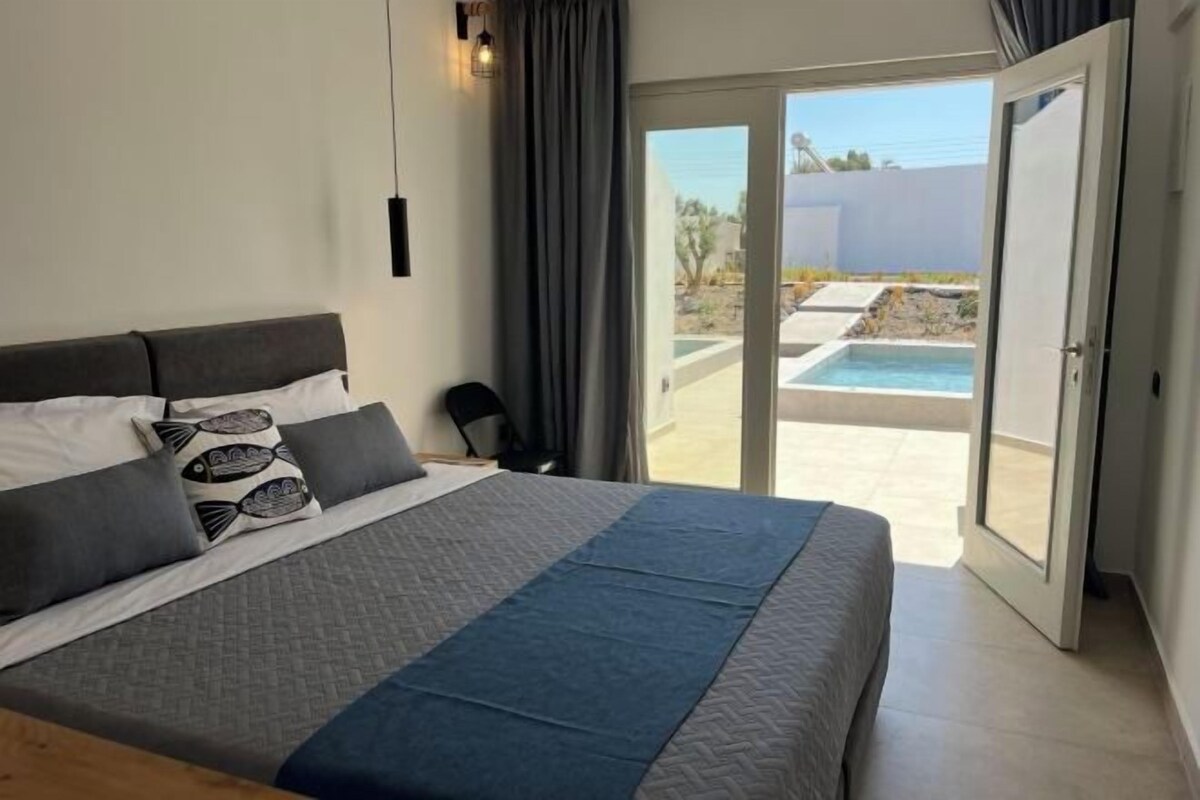 A bedroom with a bed, a view of a swimming pool, and a sliding glass door leading to an outdoor area.