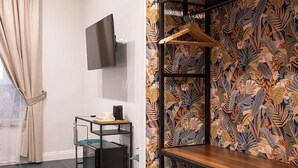 A room with a desk, a TV mounted on the wall, and a patterned wall. - Porta Cerasa (Naples)