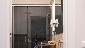 A modern bathroom with a glass-enclosed shower, a white pedestal sink, and a mirror above the sink. - Porta Cerasa (Naples)