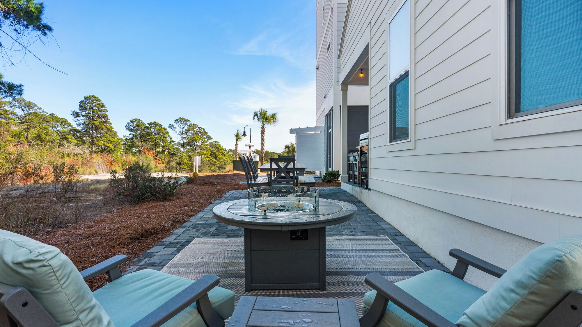 A patio with a circular table, chairs, and a fire pit.