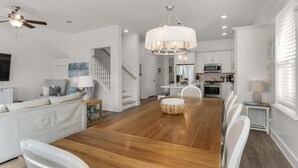 Un salón amplio con suelo de madera, una mesa de comedor y una escalera que sube a un nivel superior.