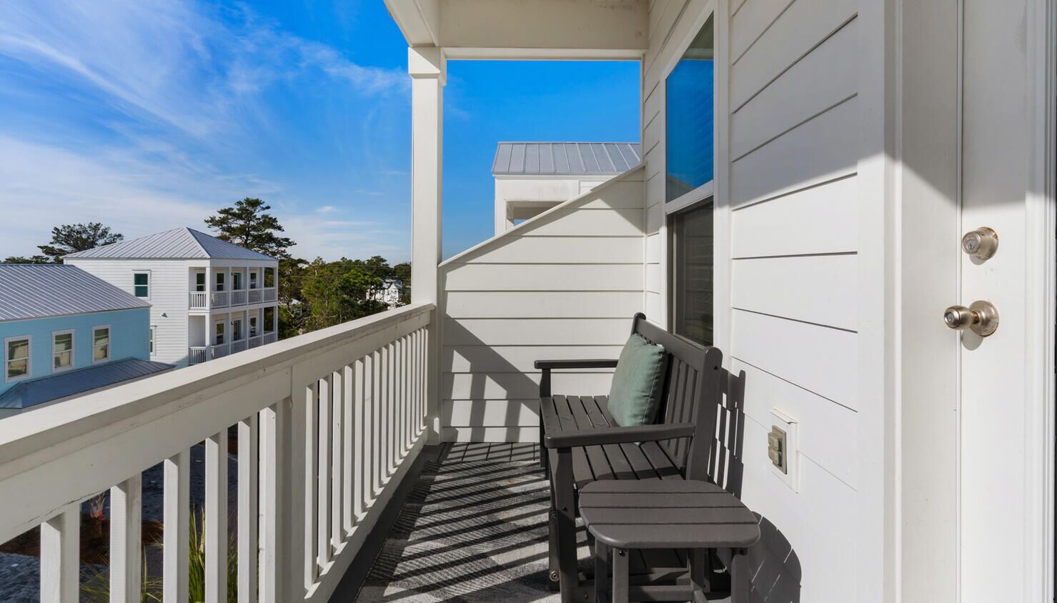 A balcony with a wooden bench and a door.