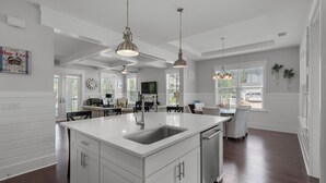 A spacious kitchen with a large island, white cabinetry, and pendant lighting.
