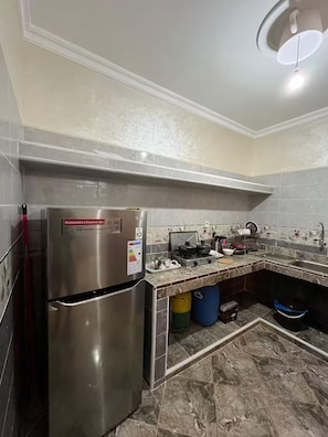 A kitchen with a stainless steel refrigerator, a gas stove, and a tiled backsplash.