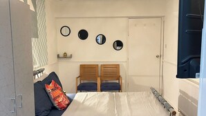A bedroom with a bed, a sofa, a mirror, and a ceiling light fixture. - King Studio (Romford)