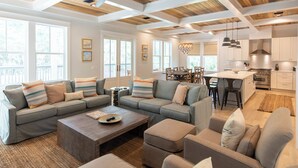 A spacious living room with a sectional sofa, a coffee table, and a dining area with a chandelier. - Seagrove - Sleeps 13 - Private Pool- Near Seaside (Santa Rosa Beach)