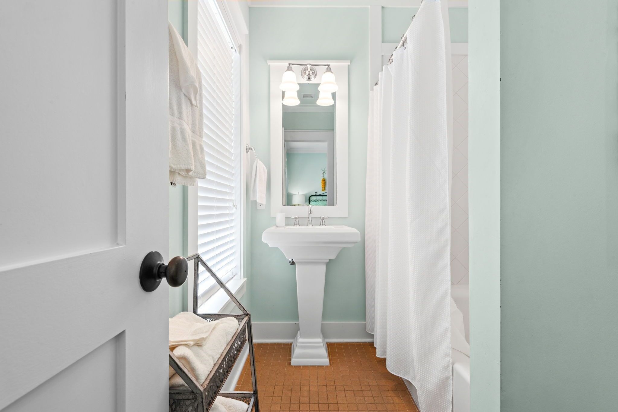 Une salle de bain avec un lavabo sur colonne, des serviettes blanches et un rideau de douche.