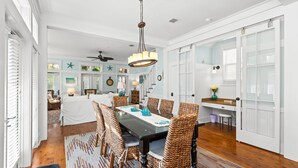 Uma sala de jantar com mesa, cadeiras e um candelabro.