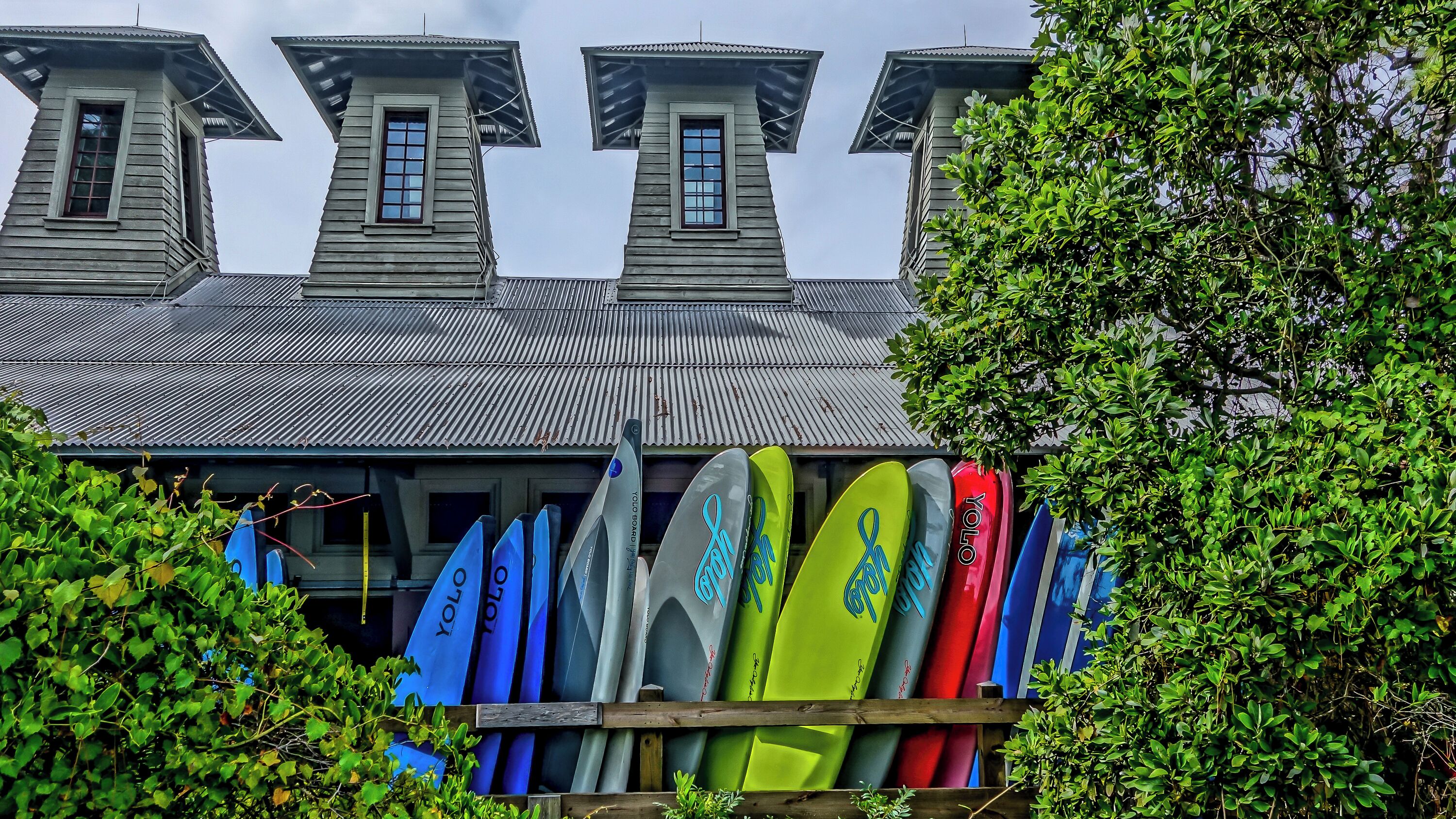 Un immeuble doté de plusieurs tours et une rangée de planches de surf devant.