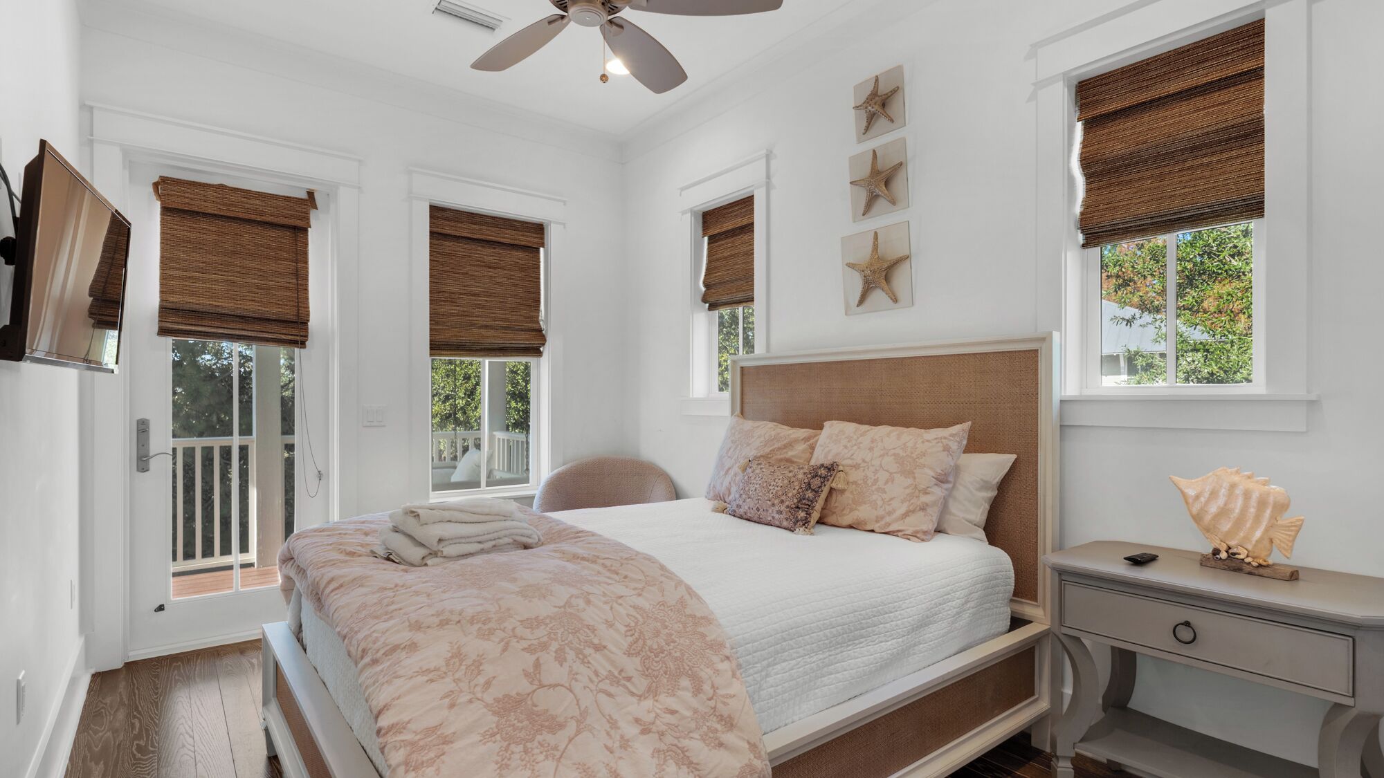 A bedroom with a bed, a nightstand, a ceiling fan, and three starfish wall decorations.