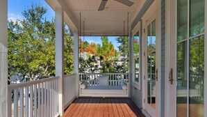 Eine überdachte Veranda mit Holzboden, weißen Geländern und einer Bank.