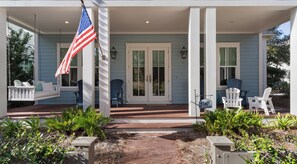 A porch with a swing, two Adirondack chairs, a flag, and a mailbox. - Access to Watercolor Pools & Beach Club - 4-bedroom Beach Oasis - Sleeps 12 (Santa Rosa Beach)