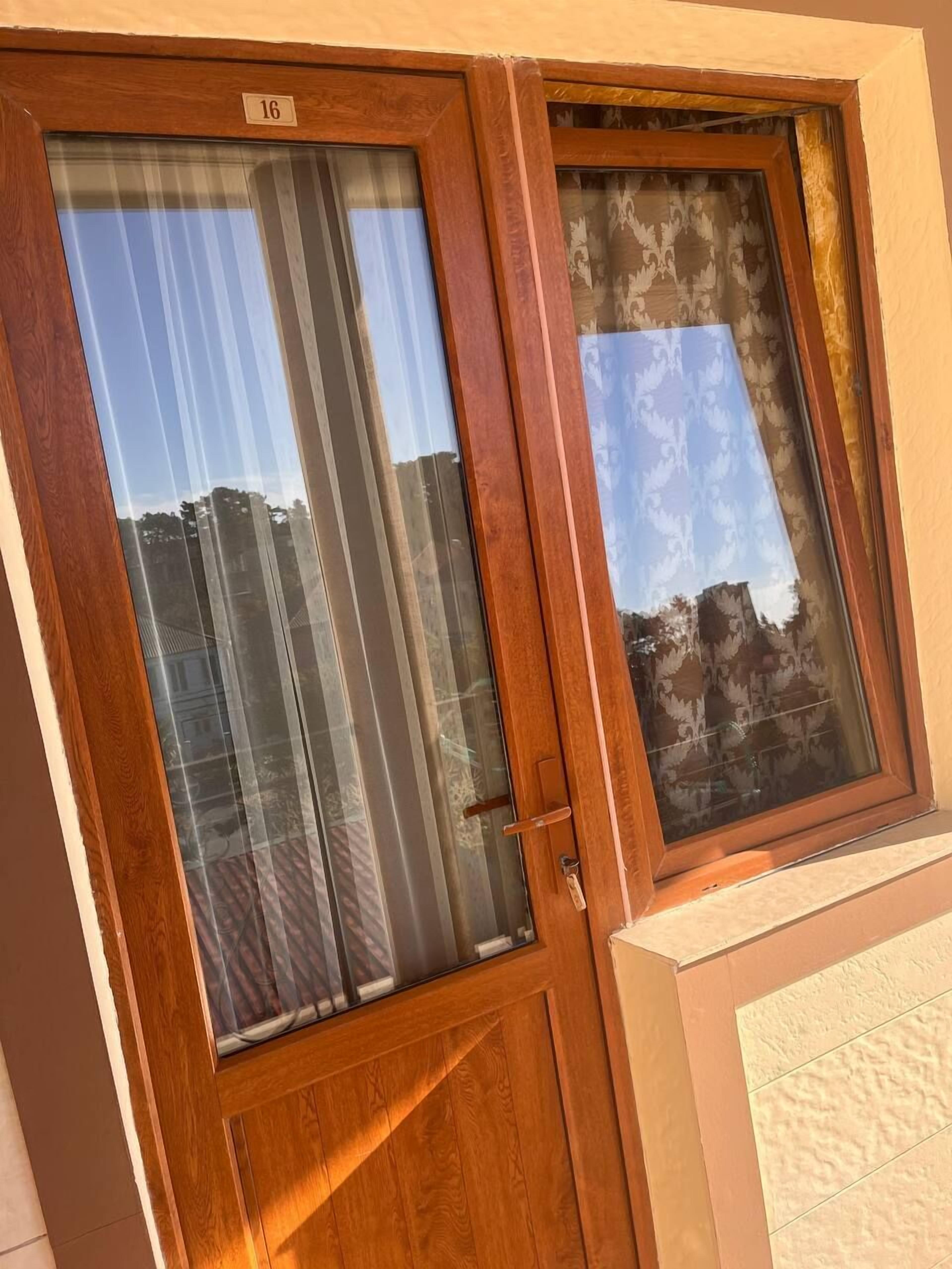 A wooden door with a number "16" on it, a glass panel with a curtain, and a patterned window.