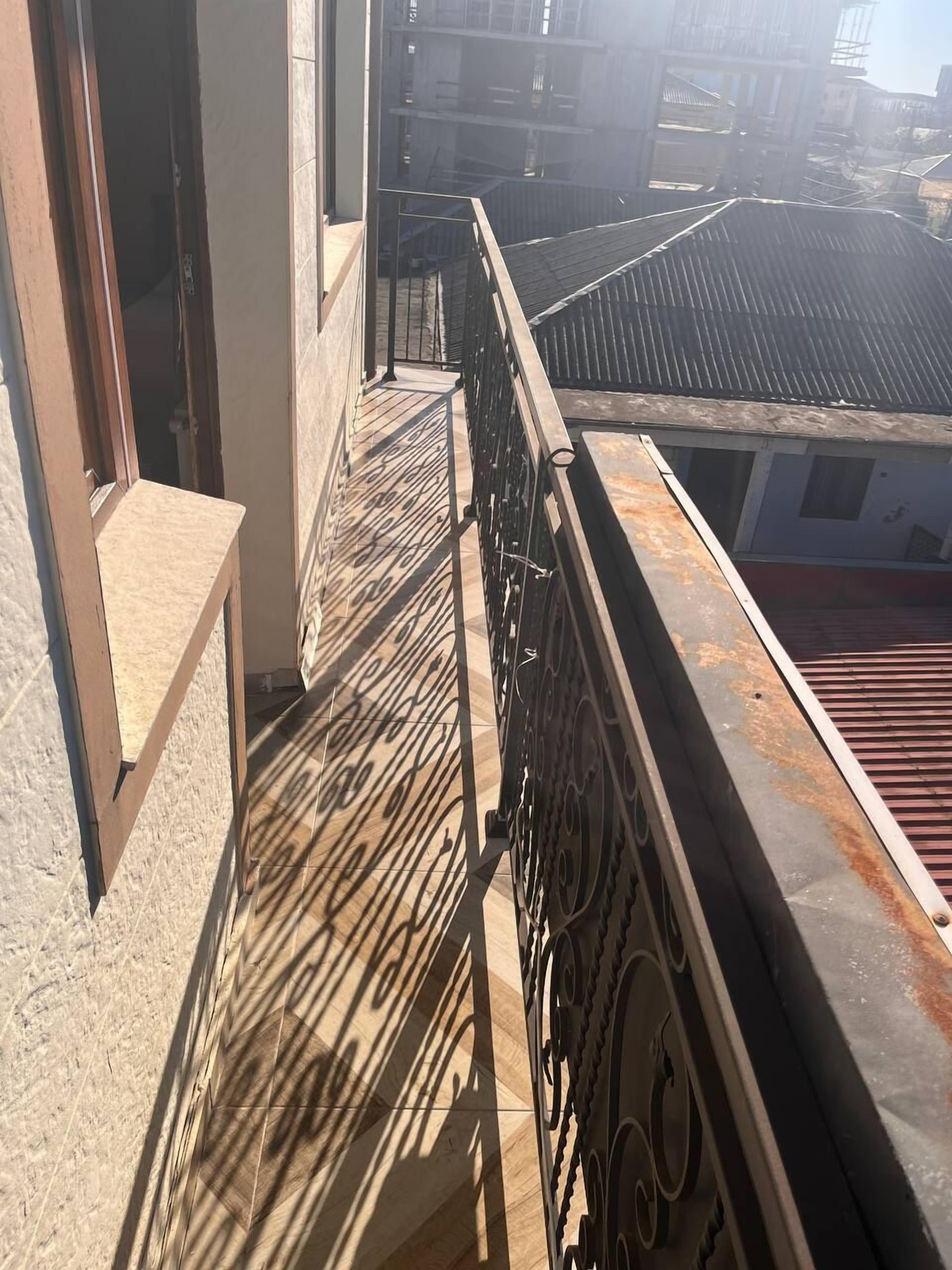 A narrow balcony with a metal railing and a view of adjacent buildings.